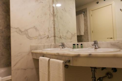 Hotel Vértice Chipiona Mar في تشايبيونا: حمام مغسلتين ومرآة