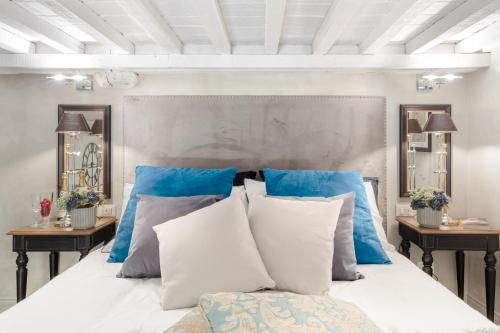 een slaapkamer met een bed met blauwe en witte kussens bij Paolo Guinigi, Elegant Apartment Suite, Masterful Interior inside the Walls of Lucca in Lucca