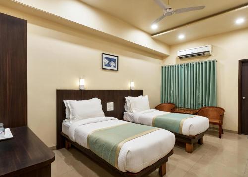 a hotel room with two beds and a desk at Hotel Atria, Kolhapur- Opposite To Central Bus Station in Kolhapur