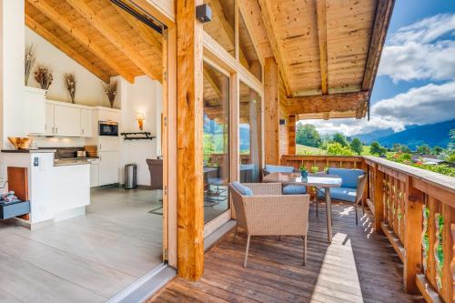 a kitchen and dining room with a balcony with a table and chairs at Chaletdorf am Sonnenhang in Neukirchen am Großvenediger