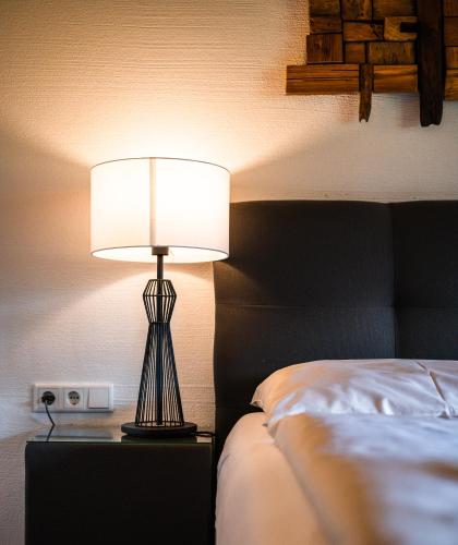 a lamp sitting on a night stand next to a bed at Chaletdorf am Sonnenhang in Neukirchen am Großvenediger