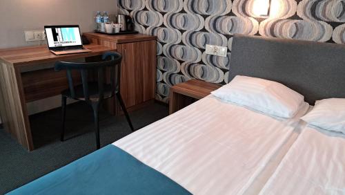 a bedroom with a bed and a desk with a laptop at Hotel Mazowiecki Łódź in Łódź