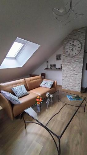sala de estar con sofá y reloj en la pared en Appartement Vallée de la Risle, en Glos-sur-Risle