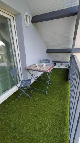 una mesa y sillas en un balcón con césped verde en Appartement Vallée de la Risle, en Glos-sur-Risle