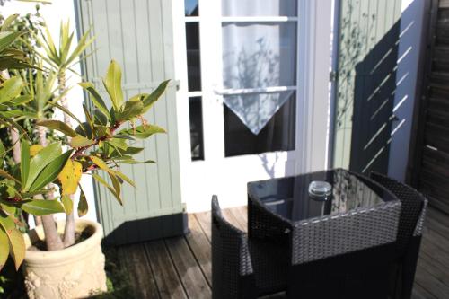 une terrasse couverte avec une table noire, des chaises et des plantes dans l'établissement Fleur de Ré, à Loix