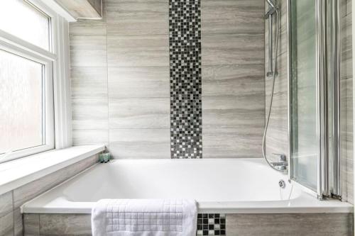 a white bath tub in a bathroom with a window at Modern Complete Cotham House #2 by Prescott Apartments in Bristol