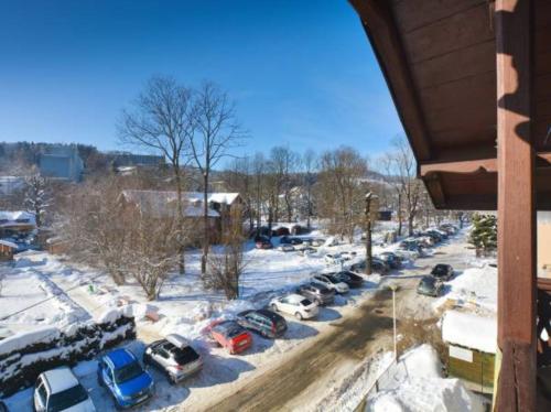a parking lot with cars parked in the snow at Willa Dniestrzanka in Krynica Zdrój