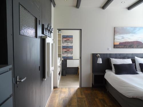 a bedroom with a large bed and a bathroom at B&B Tulden Farmhouse in Giethoorn