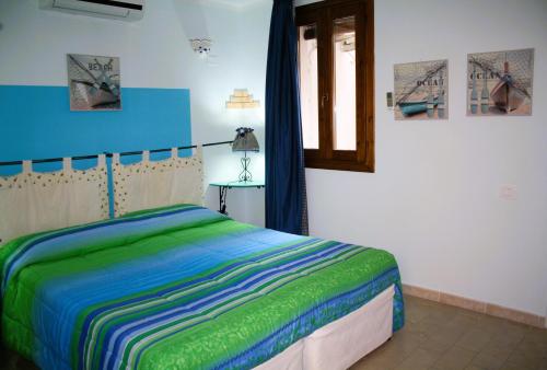 een slaapkamer met een bed met een groen en blauw dekbed bij La Pirata Capitana in Costa degli Angeli