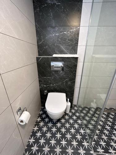 a bathroom with a toilet and a black and white tile floor at Fener Hotel Café & Kahvalti in Cesme