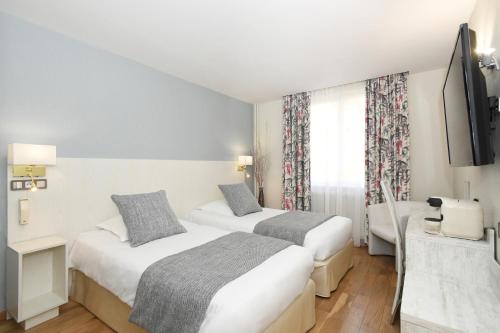 a hotel room with two beds and a television at Logis Hôtel du Centre - Halte idéale en cyclotourisme avec garage à vélos clos in Molsheim