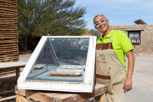a man in an apron holding a box of donuts at El Huarango Eco Lodge in La Huaica