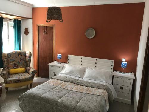 a bedroom with a large bed and a chair at Habitación independiente en casa antigua - Centro in Utrera