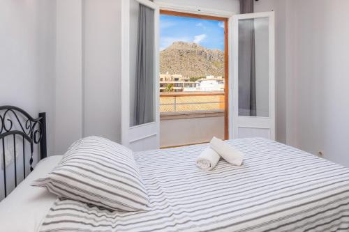 ein Bett mit zwei Kissen und ein Fenster mit Aussicht in der Unterkunft Apartamento Brisas in Port de Pollença