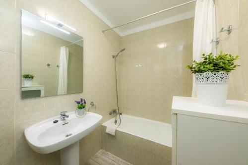 ein Badezimmer mit einem Waschbecken, einem Spiegel und einer Badewanne in der Unterkunft Apartamento Brisas in Port de Pollença