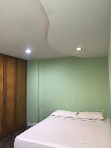 1 dormitorio con cama blanca y pared verde en Rod Fai Fah Apartment, en Bangkok