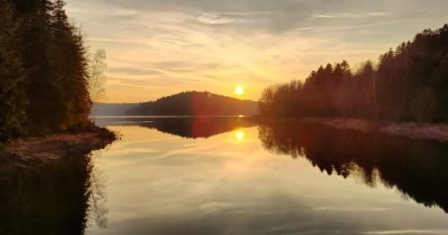 a view of a lake with the sun setting at gîte de rarounette au cœur des Vosges in Celles-sur-Plaine