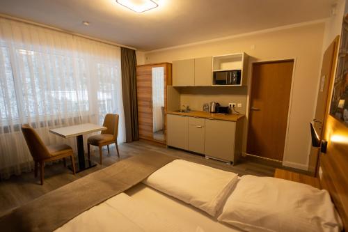 ein Hotelzimmer mit einem Bett und einem Tisch sowie einer Küche in der Unterkunft Hotel Schlangenbader Hof in Schlangenbad