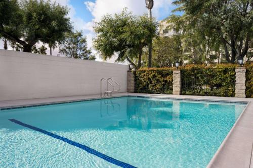 a swimming pool in front of a fence with trees at Ramada by Wyndham Anaheim Convention Center in Anaheim