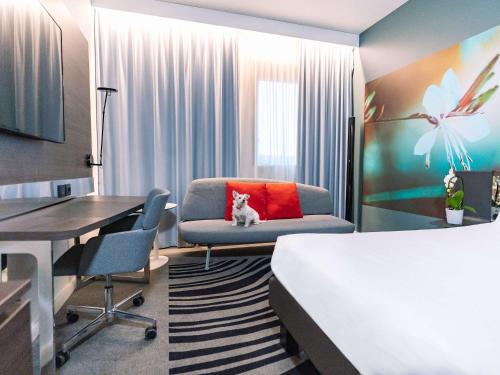 una camera d'albergo con letto, sedia e scrivania di Novotel Milano Linate Aeroporto a Milano
