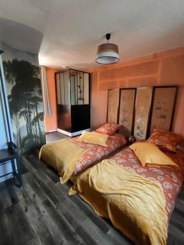 two beds in a bedroom with orange walls at Ty Merzhin in Huelgoat