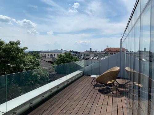 a balcony with two chairs and a view of a city at INX Design Hotel in Kraków