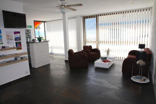 a living room with two chairs and a ceiling fan at Hotel Garni Morettina in Brissago