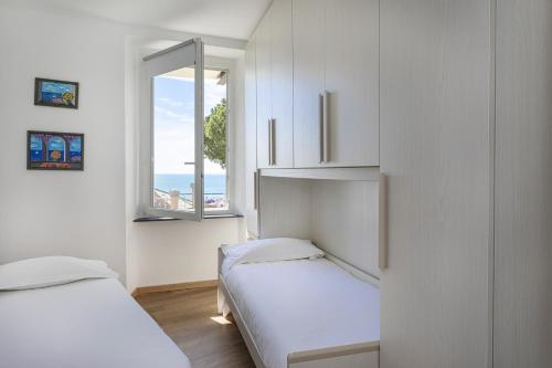 Dieses weiße Zimmer verfügt über 2 Betten und ein Fenster. in der Unterkunft Genova Wonderview by Wonderful Italy in Genua
