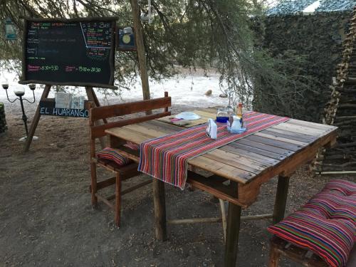 a wooden table and a bench with a table and a sign at El Huarango Eco Lodge in La Huaica