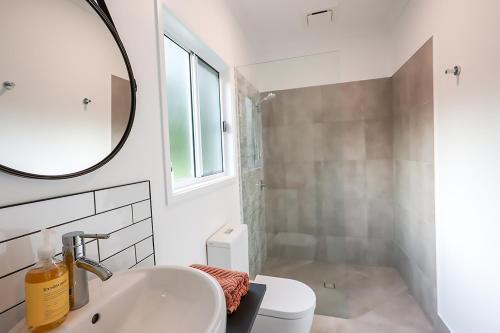 uma casa de banho branca com um lavatório e um espelho em The Poolhaus Retreat - Peaceful Private Studio em Valdora