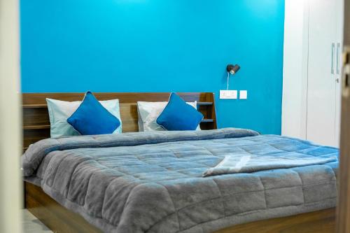 a blue bedroom with a large bed with blue walls at FlxHo Uno - Serviced Apartment & Rooms - Golf Course Road in Gurgaon