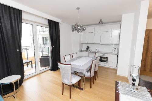 CedzynaにあるApartament Business & Living No 91 Nad Zalewem w Cedzynie, hala garażowaのテーブルと椅子のあるキッチンとダイニングルーム