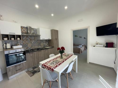 een keuken met een tafel met een vaas met bloemen erop bij Rose Rosse - Sicily Holiday House in Racalmuto