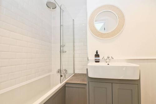 a white bathroom with a sink and a shower at WALK TO THE BEACH, spacious cottage with sea views in Saint Merryn