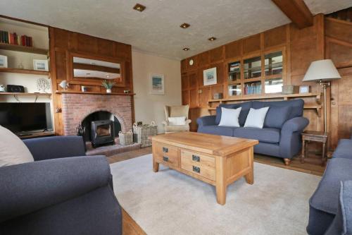 a living room with blue furniture and a fireplace at WALK TO THE BEACH, spacious cottage with sea views in St Merryn