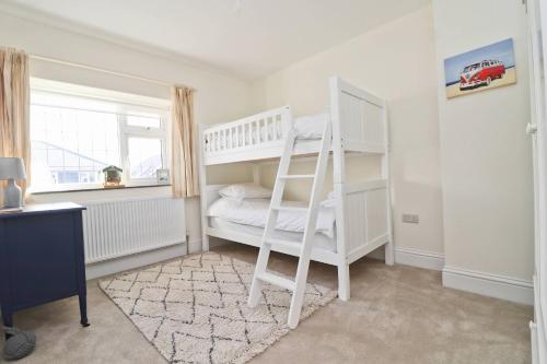 a bedroom with a white bunk bed and a window at WALK TO THE BEACH, spacious cottage with sea views in St Merryn