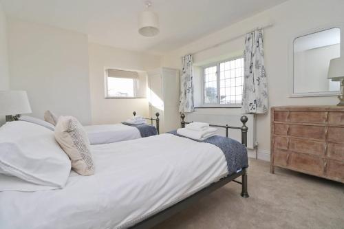 a bedroom with two beds and a dresser and two windows at WALK TO THE BEACH, spacious cottage with sea views in St Merryn