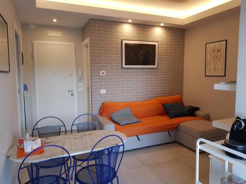 an orange couch in a room with a table and chairs at Modern Flat with lake view & private beach! in Toscolano Maderno