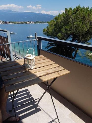 a wooden bench on a balcony with a view of the water at Modern Flat with lake view & private beach! in Toscolano Maderno