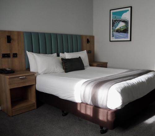 a bedroom with a large bed with a green headboard at Holiday Inn Telford Ironbridge, an IHG Hotel in Telford
