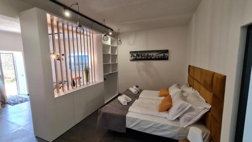 a small bedroom with a bed with white sheets and orange pillows at HIŠA KAPIŠ with HOT TUBE in Koper