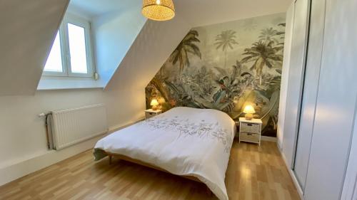 um quarto com uma cama com um quadro na parede em Chez Sandrine & Tanguy em Saint-Valery-sur-Somme