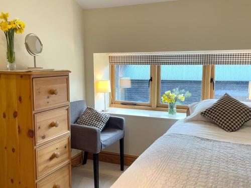 um quarto com uma cama, uma cadeira e uma janela em Rural Farm Cottage Easy Commute To Cambridge em Cambridge