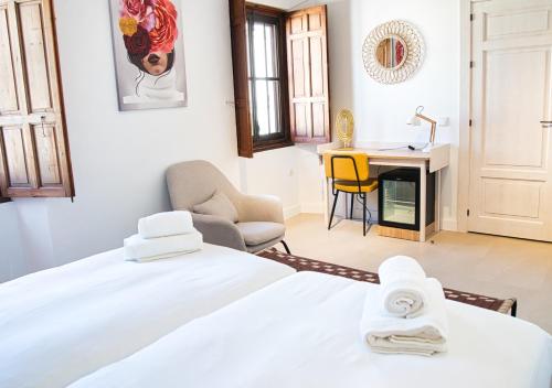 a bedroom with a bed and a desk and a chair at Casa Rural Casa Levante in Arcos de la Frontera