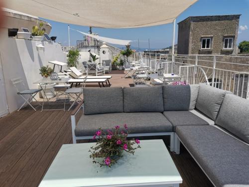 a rooftop patio with a couch and tables and chairs at Le Volte Procida Home in Procida