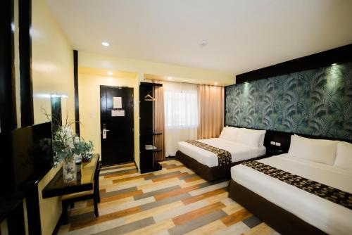 Habitación de hotel con 2 camas y escritorio en SunCity Suites en General Santos