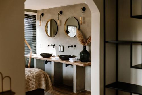 a bathroom with two sinks and mirrors on the wall at Boutique Hotel Hoog Soeren in Hoog-Soeren