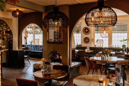 a restaurant with tables and chairs and chandeliers at Boutique Hotel Hoog Soeren in Hoog-Soeren