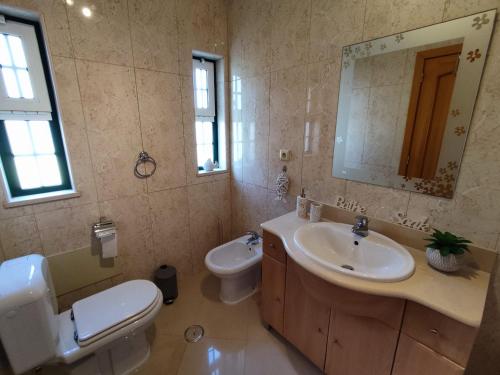 een badkamer met een wastafel, een toilet en een spiegel bij 1D Areias de Porches, Pool & A/C - Casas & Papéis in Armação de Pêra