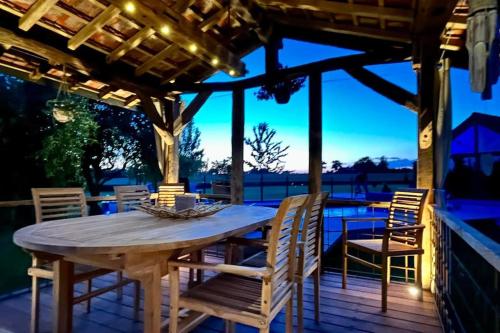 - une table et des chaises en bois sur une terrasse la nuit dans l'établissement Les Sources d'Hon - Gîte & Espace wellness, 